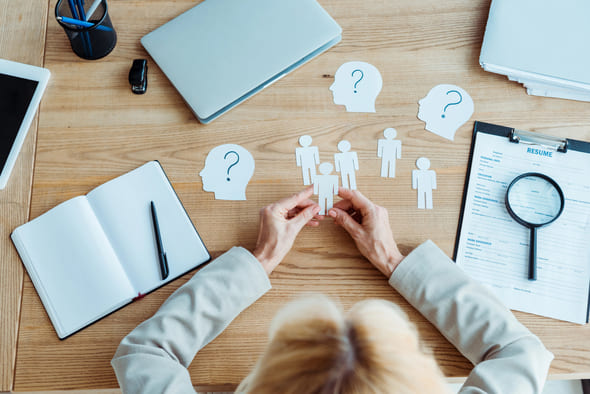 Bird's eye view of a table with a person looking at paper people